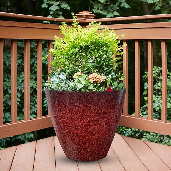 Large red speckled planter with green shrubs and flowers on a wooden deck balcony
