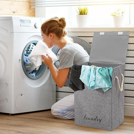 Woman checking laundry in front-load washing machine with gray fabric laundry basket full of clothes