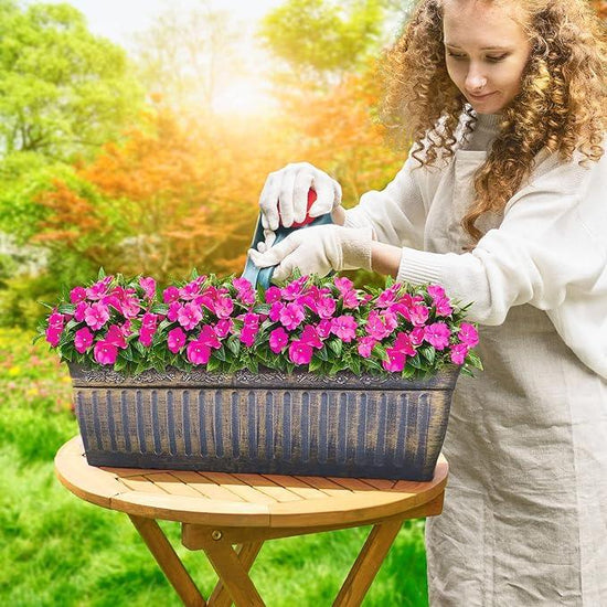 Young woman watering vibrant pink flowers in a decorative window box planter outdoors