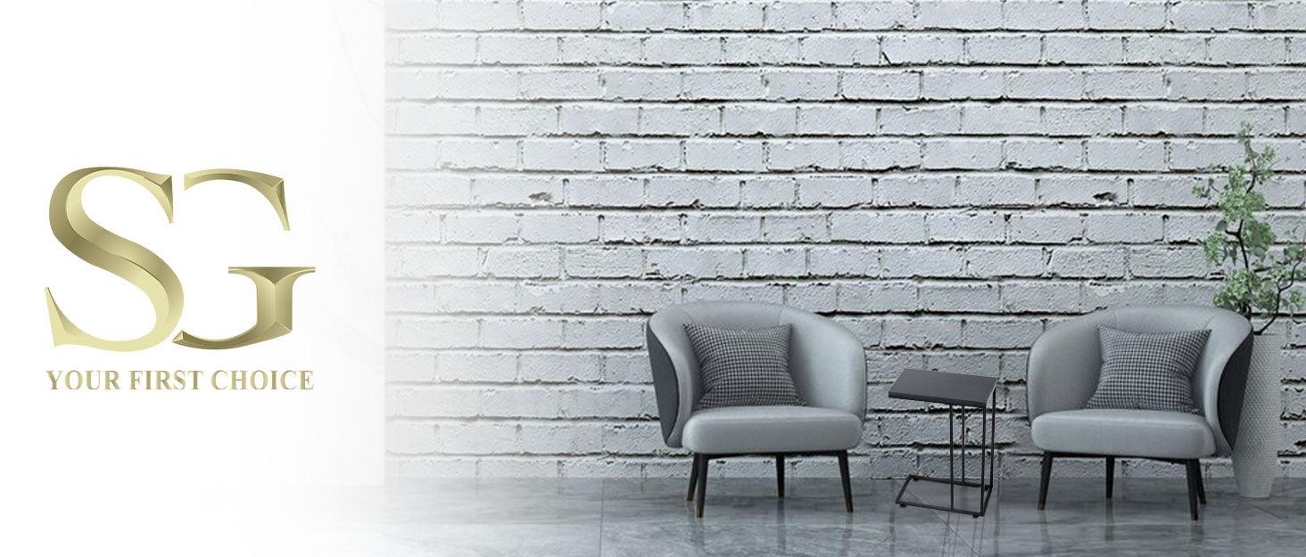 Modern living room with two gray armchairs, a small black side table, and a plant against a white brick wall