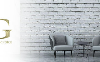 Modern living room with two gray armchairs, a small black side table, and a plant against a white brick wall